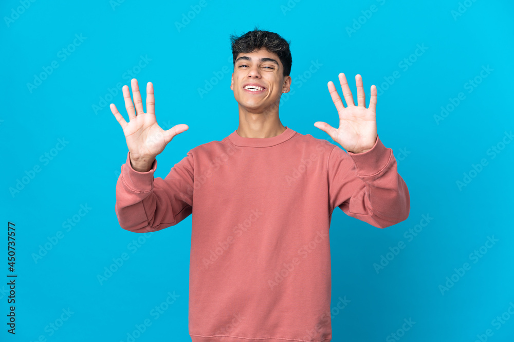 Naklejka premium Young man over isolated blue background counting ten with fingers