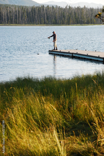 A solitary angler fishing off a dock. 