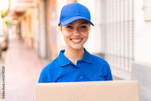 Young delivery woman at outdoors holding boxes with happy expression © luismolinero