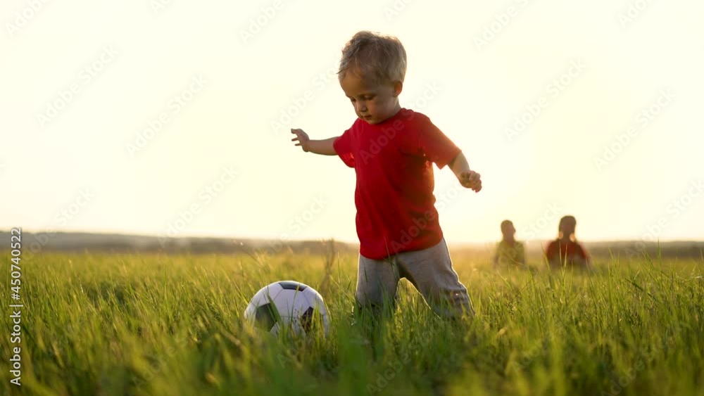 Happy family of children run across field. Group of children are playing with soccer ball. Happy family in park.Ball game in park. Family soccer game. Happy children in park run with ball.Happy family