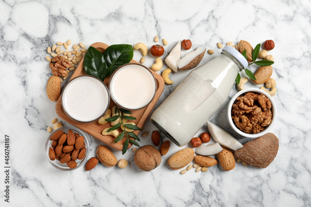 Vegan milk and different nuts on white marble table, flat lay Vegan milk and different nuts on white marble table, flat lay