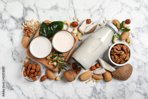 Vegan milk and different nuts on white marble table, flat lay