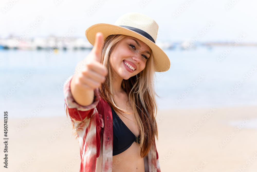 Young pretty woman in summer holidays at beach with thumbs up because something good has happened