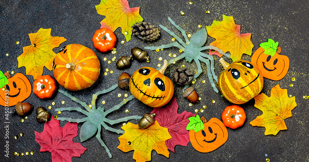 Bright Halloween banner with decorative pumpkins and funny colorful decorations on dark rustic background top view.