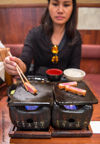 woman cooking beef katsu on traditional Japanese clay stove photo