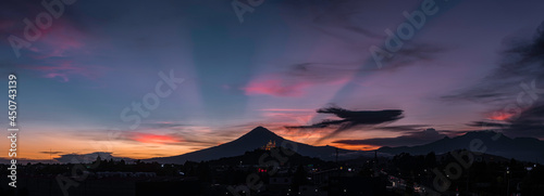 Panorama of a sunset with two volcanos and a church photo