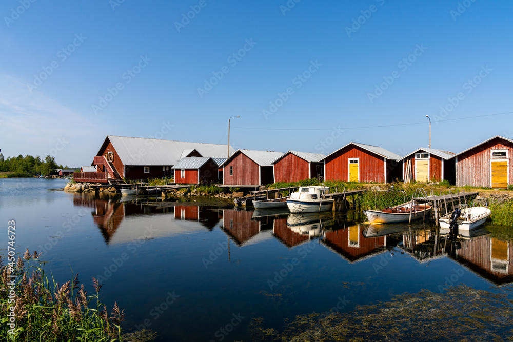 colorful fishing cottages and boats reflected in the water under a blue sky