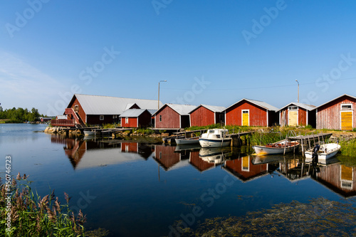 colorful fishing cottages and boats reflected in the water under a blue sky