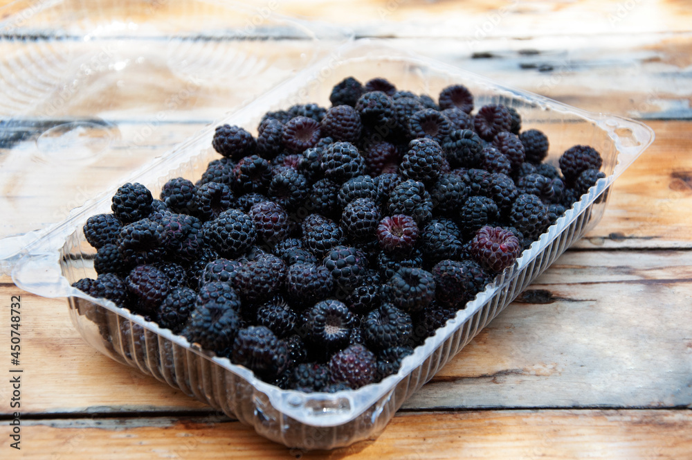 Blackberries in a transparent container on a wooden table. High quality photo Blackberries in a transparent container on a wooden table. High quality photo