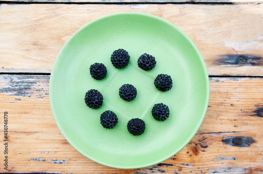 Blackberry pattern on a green plate. The plate stands on a wooden table. High quality photo