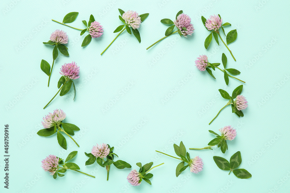 Fototapeta premium Frame of beautiful clover flowers on turquoise background, flat lay. Space for text