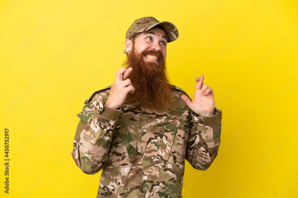 Military Redhead man over isolated on yellow background with fingers crossing Military Redhead man over isolated on yellow background with fingers crossing