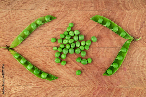Green peas, in an open pod and separately green peas, on a wooden board
