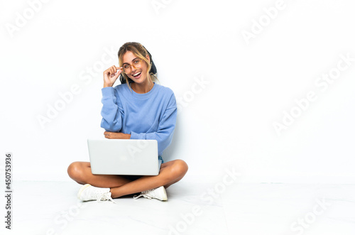 Young blonde Uruguayan girl with the laptop isolated on white background with glasses and happy