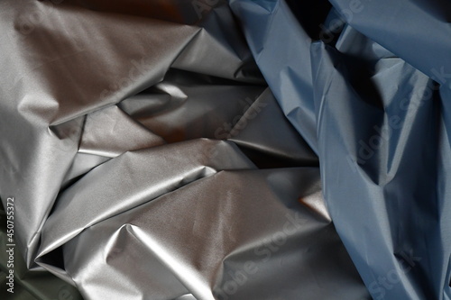 Silver and blue bolognese fabric lies in soft folds. Textile background. The texture of the fabric. Deep shadows