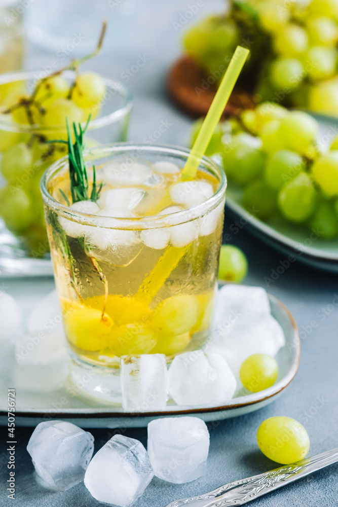 Refreshing summer drink in glass with ice cubes, green grape and rosemary on the table. Refreshing summer drink in glass with ice cubes, green grape and rosemary on the table.