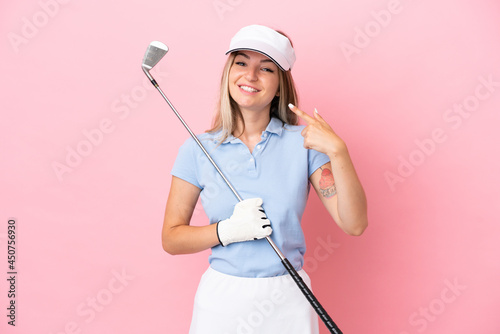 Young golfer player woman isolated on pink background giving a thumbs up gesture