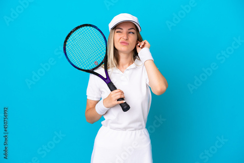 Young tennis player Romanian woman isolated on blue background frustrated and covering ears © luismolinero