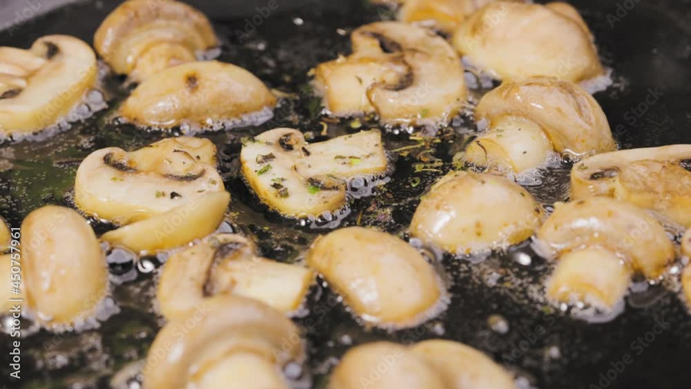 Golden slices of champignons with onion and seasoning are fried into a hot pan with oilin close up. Delicious mushroom dish. Beautiful wallpaper of cooking for restaurant. Slow motion. Golden slices of champignons with onion and seasoning are fried into a hot pan with oilin close up. Delicious mushroom dish. Beautiful wallpaper of cooking for restaurant. Slow motion.