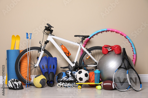 Bicycle and different modern sport equipment near beige wall