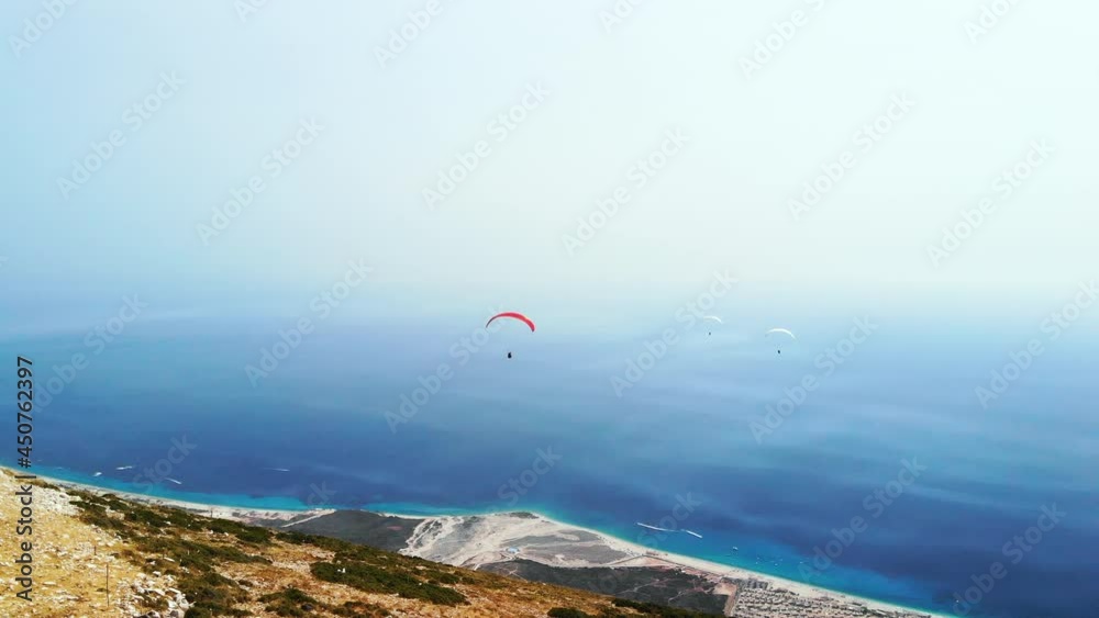 Extreme paraglider flying against a clear blue sky, sunbeam shines into camera. Man with instructor flies with parachute. 4k, slow motion. Extreme paraglider flying against a clear blue sky, sunbeam shines into camera. Man with instructor flies with parachute. 4k, slow motion.