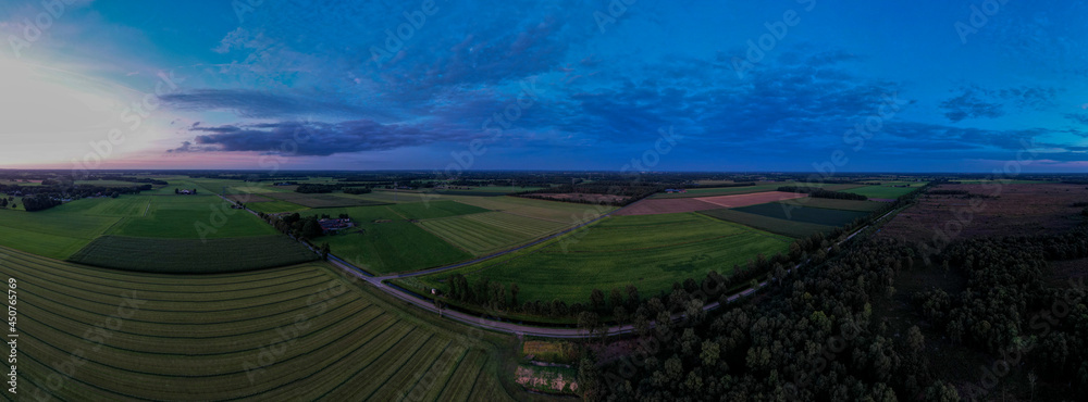 Blue hour aerial 180 degrees panorama of Dutch farmland landscape with colorful sunset in the sky. Agriculture farmland food industry.