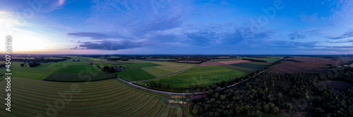 Aerial 180 degrees panorama of Dutch farmland landscape with colorful blue hour sunset in the sky. Agriculture farmland food industry.