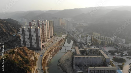 Drone shot flying over Yanchuan valley city. Aerial of Chinese historic small town, narrow between two mountains with river on misty day. photo