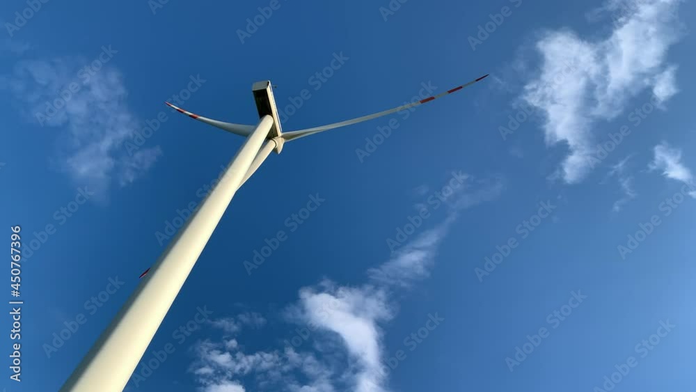 Windmill isolated on blue sky on a beautiful bright day. Rotating propellers generating electricity on a tall windmill turbine. Alternative renewable power generation. Green energy concept. Windmill isolated on blue sky on a beautiful bright day. Rotating propellers generating electricity on a tall windmill turbine. Alternative renewable power generation. Green energy concept.