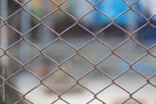 Old mesh wire fence with blurred background.