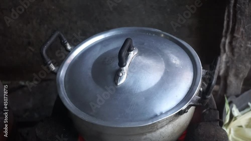 Close-up of iron pot with lid standing on the wood in fire Cooking food at fire in wild.
