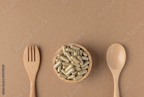 Capsual of herb in wooden small bowl with spoon.Medicine is a food. photo