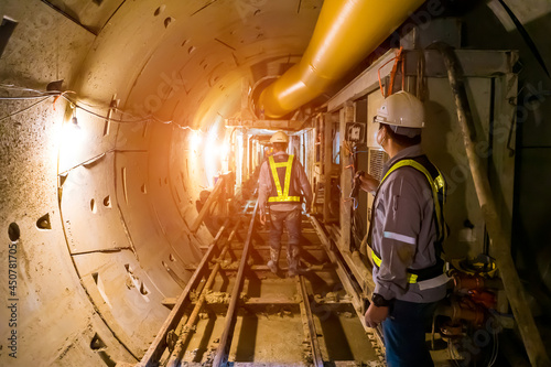 soft focus of Engineers wear helmet,vests safety .Technician control underground tunnel construction at working shaft to maintenance.Transport pipeline by Tunnel Boring Machine(TBM) method for train.
