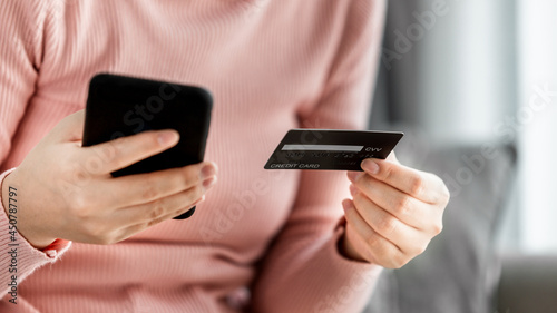 Close up of young women shopping online on a smartphone with payment via credit card, Female modern lifestyle at home, digital banking, cashless, E-commerce concept.