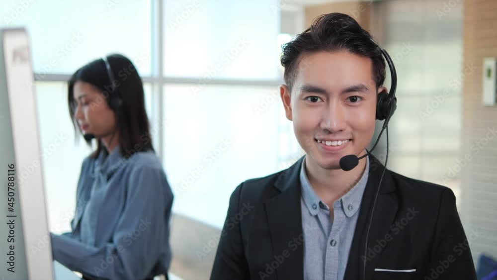 Portrait of Asian businessman smiling to camera wearing headset telemarketing customer service agent team in office to support remote customer. Call center job concept. Portrait of Asian businessman smiling to camera wearing headset telemarketing customer service agent team in office to support remote customer. Call center job concept.