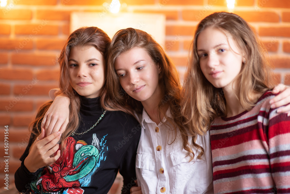 Three young beautiful girls, girlfriends on the background of a brick wall indoors. Three young beautiful girls, girlfriends on the background of a brick wall indoors.