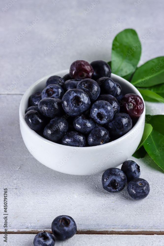 Freshly picked blueberries in a bowl. Juicy and fresh blueberries with green leaves on rustic table. Concept for healthy eating and nutrition Freshly picked blueberries in a bowl. Juicy and fresh blueberries with green leaves on rustic table. Concept for healthy eating and nutrition
