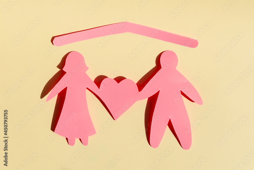 Cardboard figures of two people holding a heart under a roof symbolizing protection. The concept of social protection and insurance protection of the family.