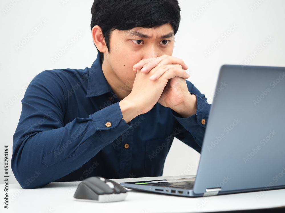 Man working from home and looking at laptop on the table feeling serious about job Man working from home and looking at laptop on the table feeling serious about job