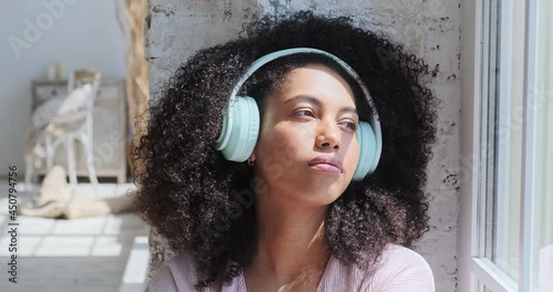 A gorgeous mixed-race woman is captivated by the pleasant sensations as she listens to relaxing music on her phone. A break from freelance work, as well as a search for inspiration and creativity photo
