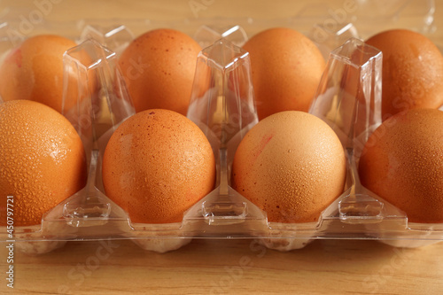 Organic chicken eggs in plastic packaging on brown wooden table            photo