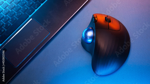 Wireless Trackball Computer mouse near the laptop on a blue background photo