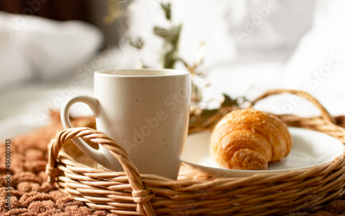Breakfast tray on the bed in the hotel room. breakfast in a snow-white bed  coffee with a croissant on a wicker tray. Morning