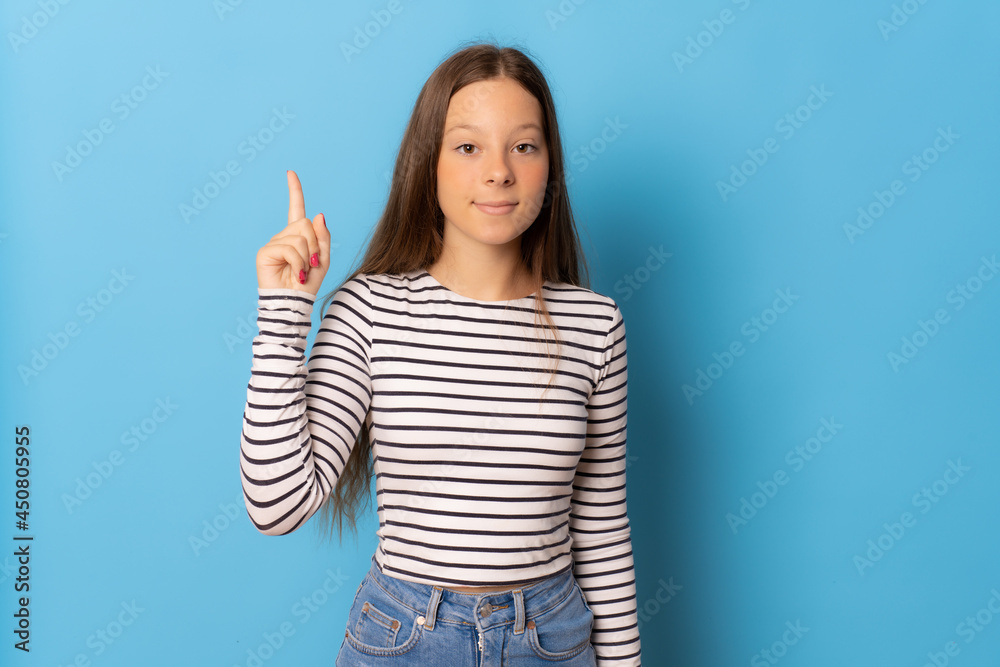Young girl pointing finger up isolated over blue background. Young girl pointing finger up isolated over blue background.