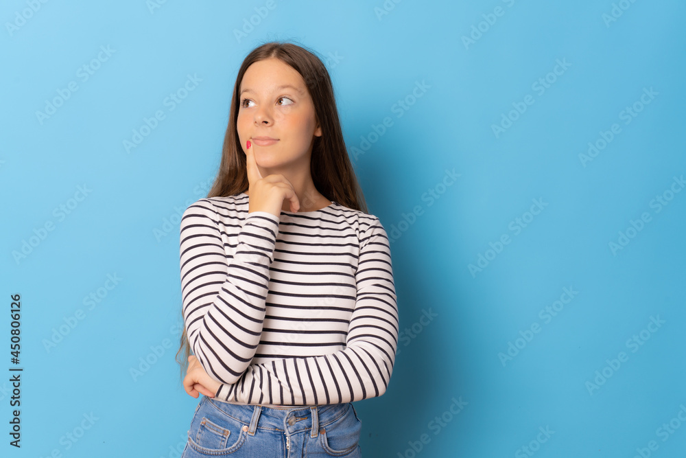 Pensive young woman in striped t-shirt isolated over blue background.
