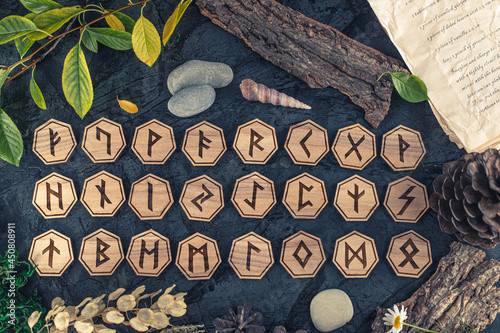 Wooden runes are lying on the table among various objects. Astrology and esotericism. Senior Futhark photo