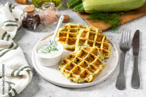 Homemade zucchini waffles in a white plate on a light gray culinary background closeup