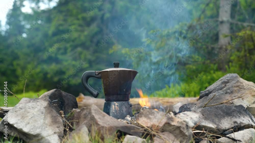 Coffee is prepared in a geyser coffee maker on a campfire in the forest Coffee is prepared in a geyser coffee maker on a campfire in the forest