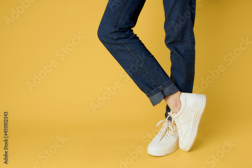 Obraz na plátně female feet cropped view white shoes fashion yellow background