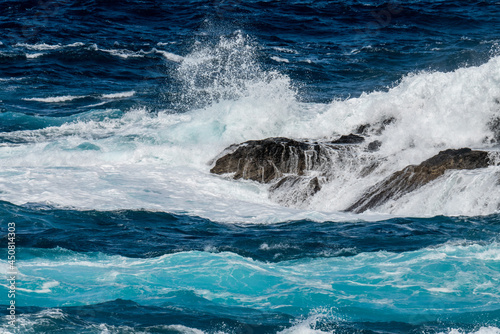 Atlantik ocean rollers breaking on black lava rocks at the north coast of Madeira in front of the promenade of Porto Moniz